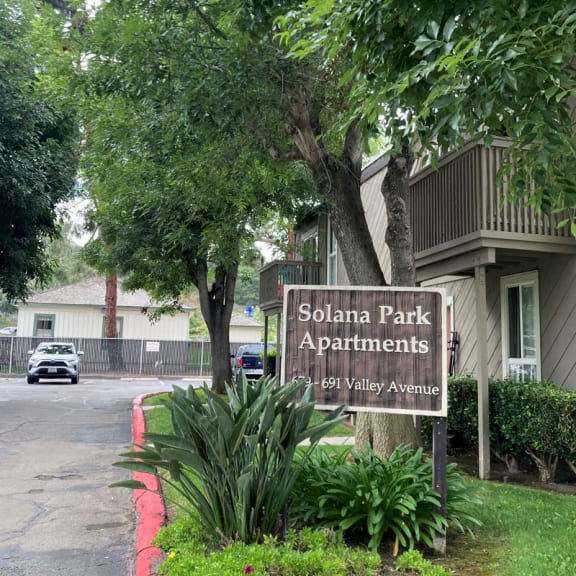 a sign in the grass in front of a building