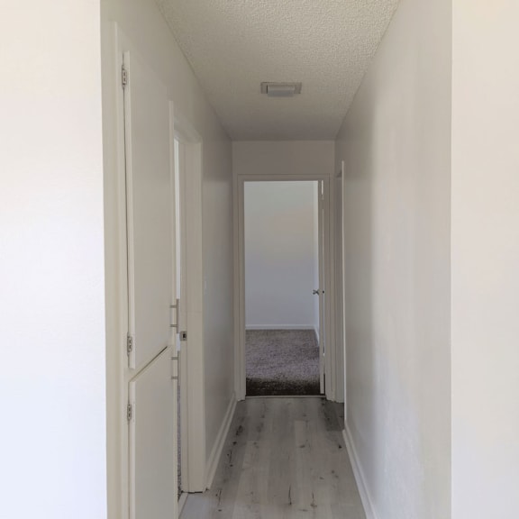 a long hallway with white walls and wood floors