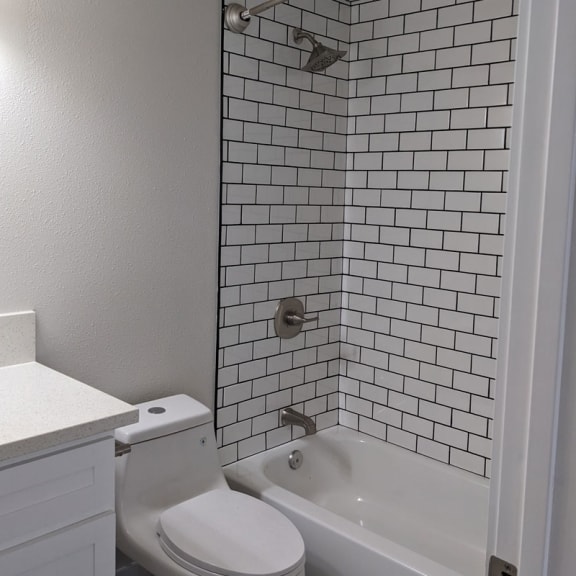 a bathroom with white tiles and a white toilet