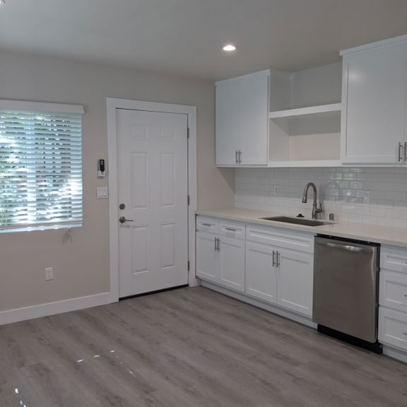 a kitchen with white cabinets and a stainless steel dishwasher