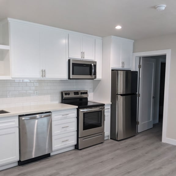 a kitchen with white cabinets and stainless steel appliances