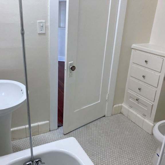 A white bathroom with a toilet, sink, and a cabinet.