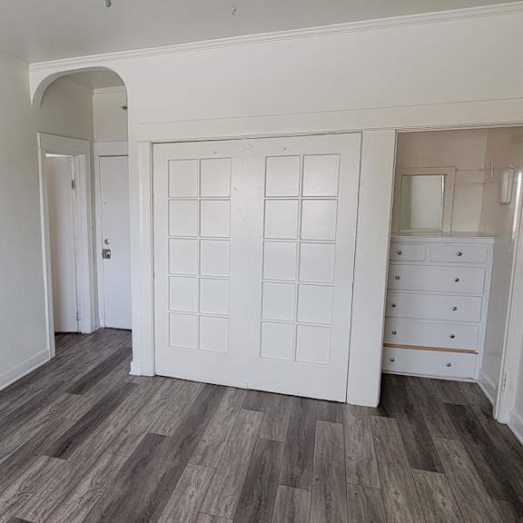 A white door with a window in the middle is in a room with wooden flooring.