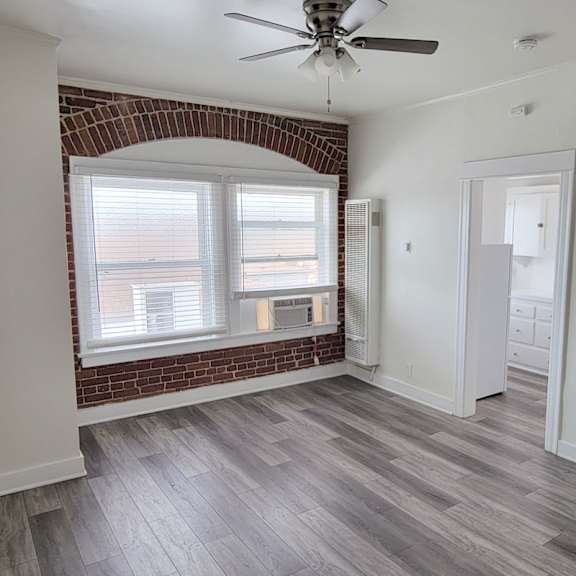 A room with a brick wall and a ceiling fan.
