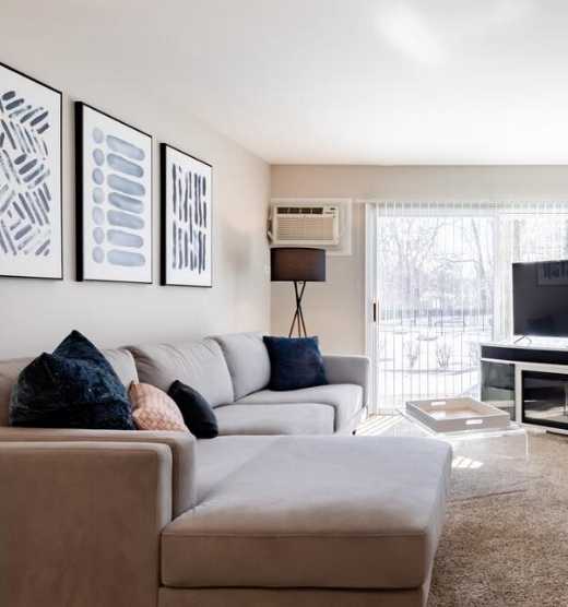A modern living room with a grey couch, a wooden coffee table, and a flat screen TV.