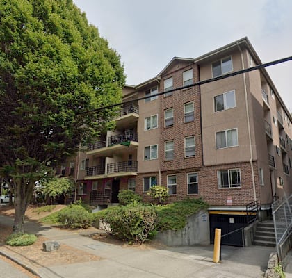 A brown apartment building with a tree in front.