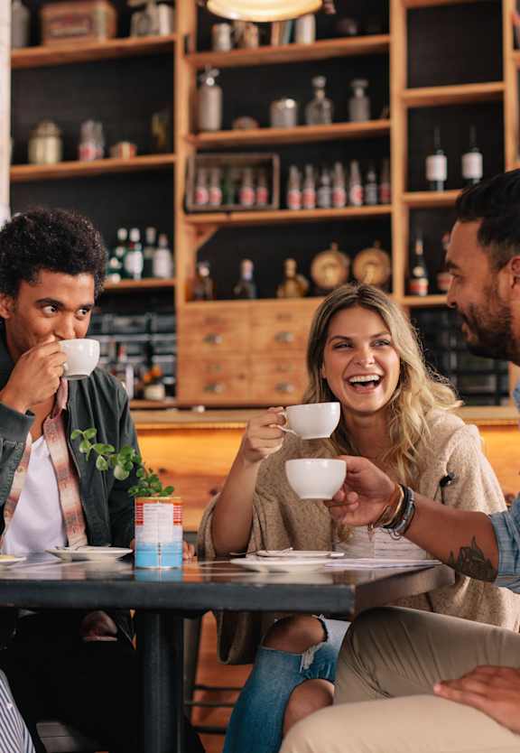 A man and a woman are sitting at a table, smiling and enjoying a drink together.