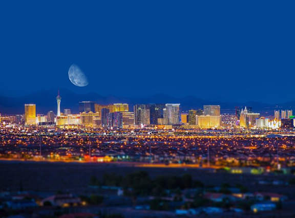 the skyline at night with a moon above the city