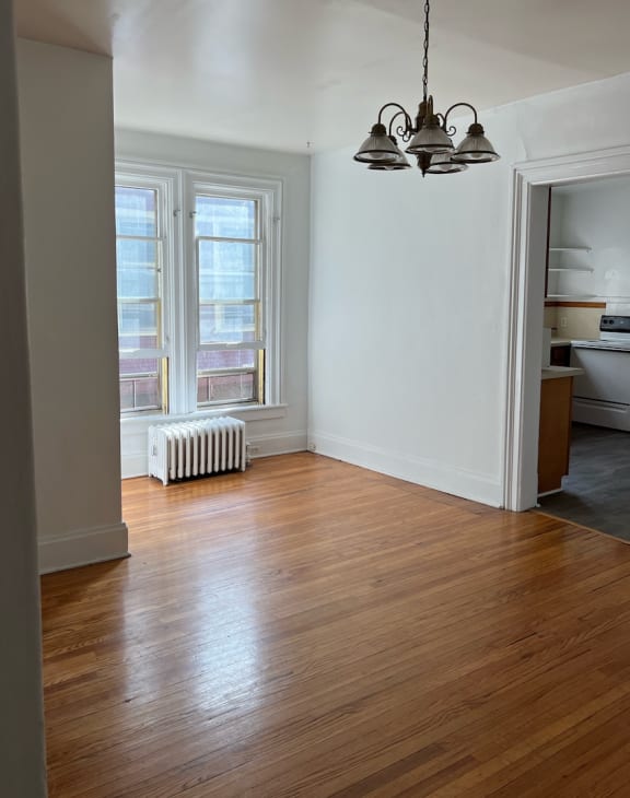an empty living room with hardwood floors and a chandelier