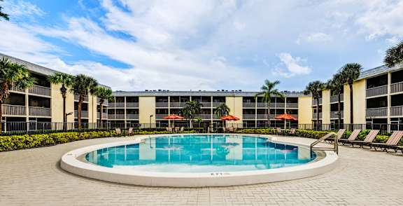 Resort-style swimming pool with lounge seating at Coronado Springs Apartments in Palm Springs, FL. Pet-friendly community offering one- and two-bedroom homes.