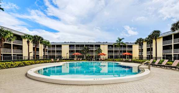 Resort-style swimming pool with lounge seating at Coronado Springs Apartments in Palm Springs, FL. Pet-friendly community offering one- and two-bedroom homes.