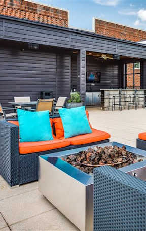 A patio with orange and blue couches and a fire pit.