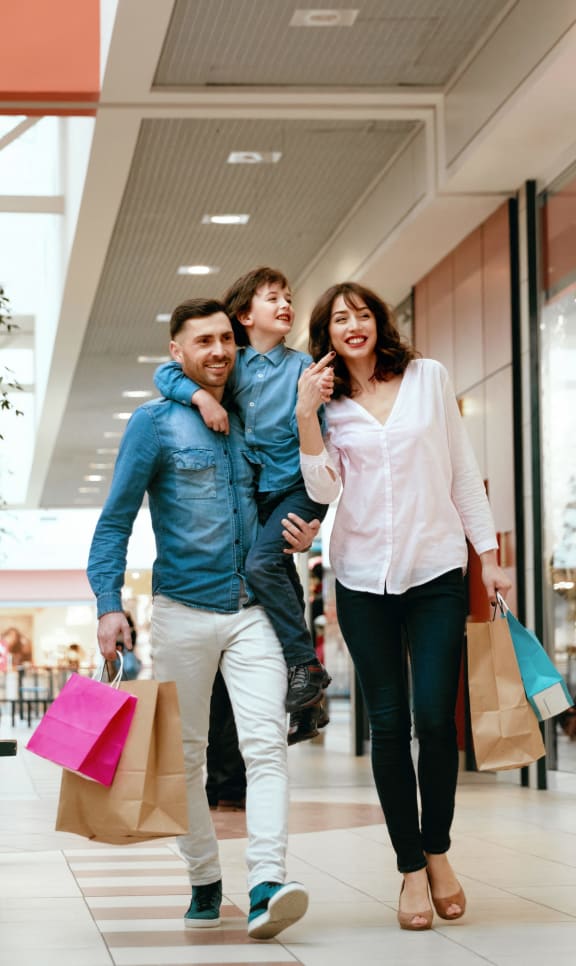 a group of people walking through a shopping mall with shopping bags