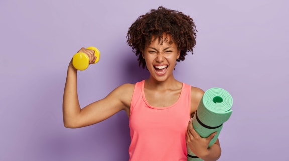 a woman in a pink tank top holding a yoga adaptor and a dumbbell at Birdie on Woodland Greens, Austin, Texas