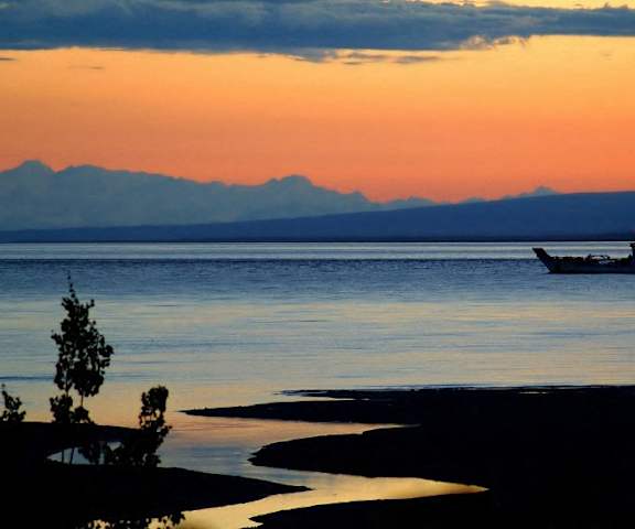 A boat on the water at sunset with mountains in the background at Brighton Park. 
