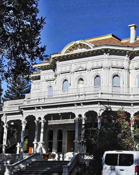 A large white building with a brown roof and a van parked in front.