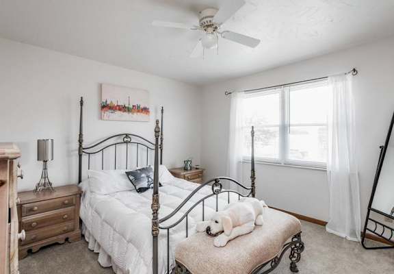 A bedroom with a four poster bed and a dog on the foot of the bed.