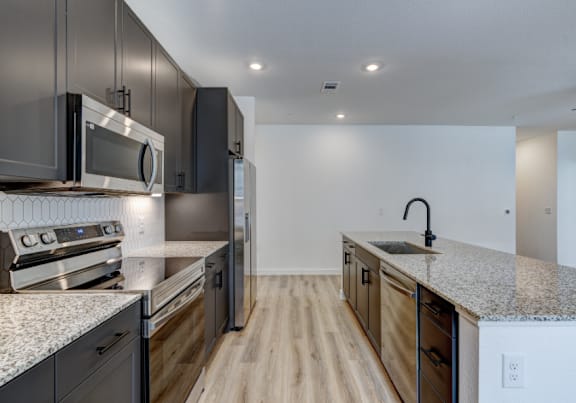 A modern kitchen with dark wood cabinets and stainless steel appliances.