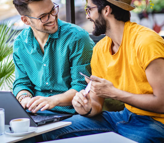 Couple looking at each other and smiling while searching for their next home at a coffee shop