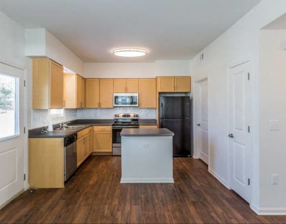 a kitchen with wooden cabinets and a black refrigerator
