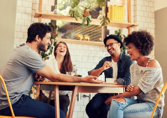 Lifestyle photo of friends laughing around a table