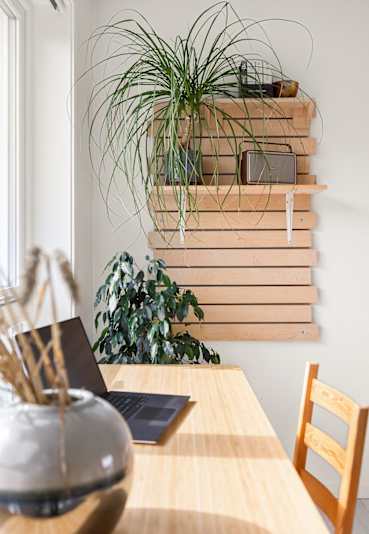 Wooden table with a laptop and decorative vase at Eden West Apartments.