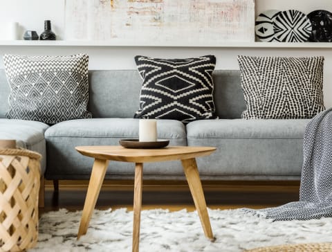 Blue couch with wood coffee table in front of it and elephant ear plant next to it and art above the wall.