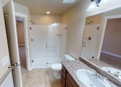 Thumbnail 12 of 17 - A bathroom with a walk-in shower, toilet, and sink.
