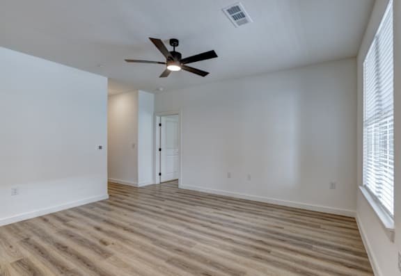 A room with a ceiling fan and wooden flooring.