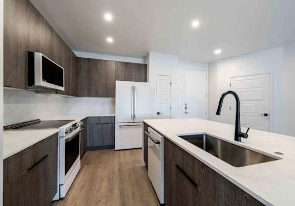 A modern kitchen with white countertops and stainless steel appliances.