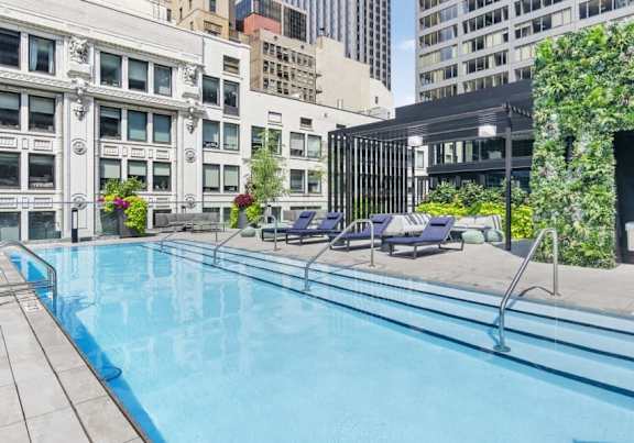 A swimming pool surrounded by lounge chairs and buildings.