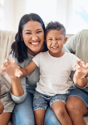 a family sitting on a couch smiling and waving to the camera