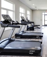a gym with treadmills and weights on a wooden floor