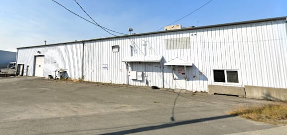 the side of a white building with a parking lot