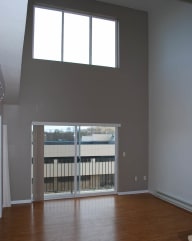 an empty room with a large window and wooden floors