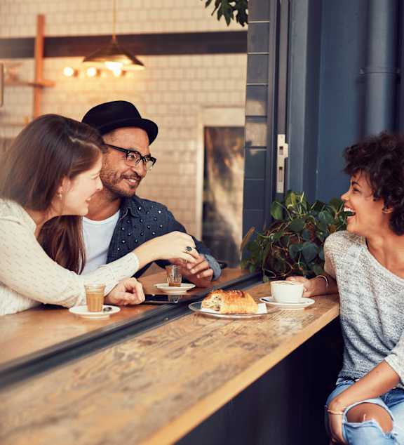 Three people are sitting at a table in a cafe.