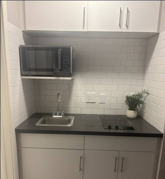 a small kitchen with white cabinets and a stainless steel refrigerator