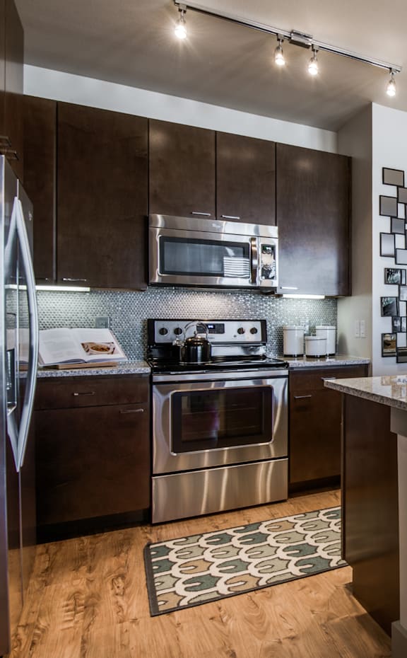 A modern kitchen with dark wood cabinets and stainless steel appliances.