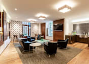 Thumbnail 1 of 23 - A modern living room with a glass table and black chairs.