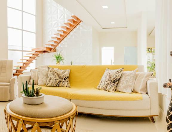 a living room with a yellow couch and white chairs