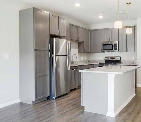 an open kitchen with stainless steel appliances, grey cabinets, and granite counter tops