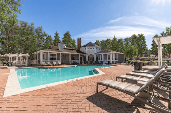 A pool area with sun loungers and a building in the background.