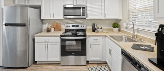 A modern kitchen with white cabinets and stainless steel appliances.