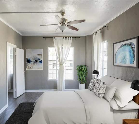 A bedroom with a large bed and a ceiling fan.
