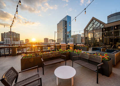 a rooftop patio with seating and a view of the city at sunset