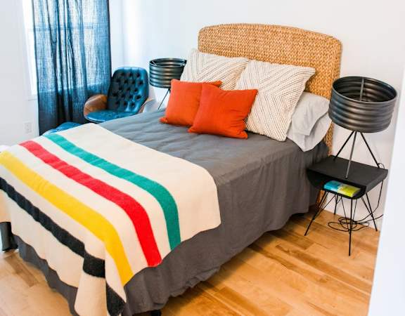 a bedroom with a bed with a striped comforter and orange pillows