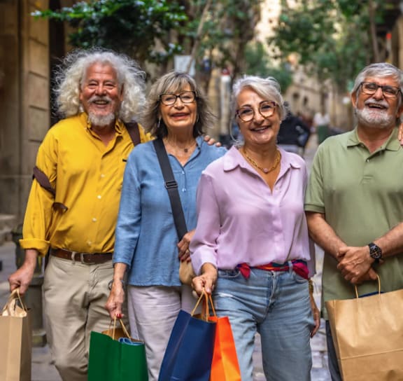 A group of five people are walking down a street holding shopping bags.