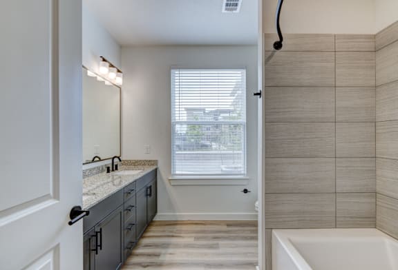 A bathroom with a tub, sink, and a window.