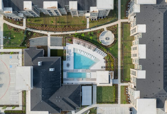 A bird's eye view of a building with a swimming pool in the middle.