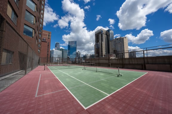 a tennis court on the roof of a building with the city skyline in the background